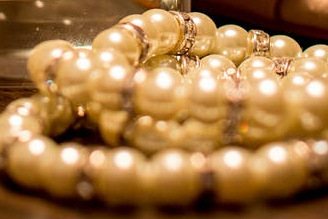 brown glass fragrance bottle beside white pearl bracelets